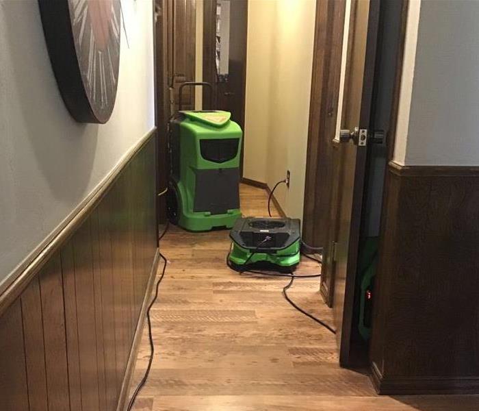 Green air mover and green dehumidifier set up in the hallway of a home.
