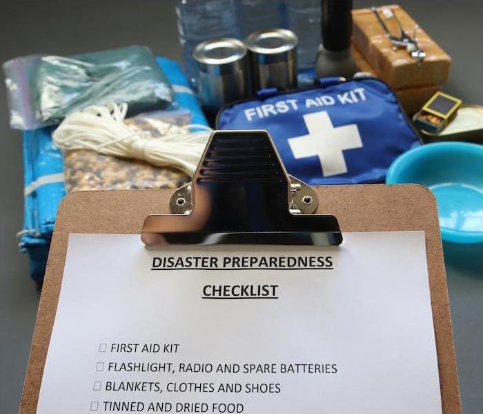 clip board with a disaster preparedness checklist and emergency supplies in the background
